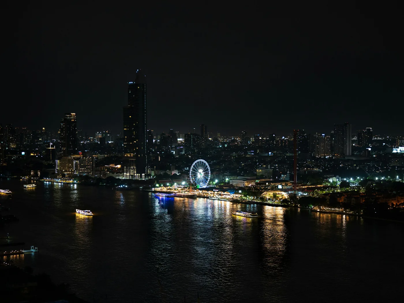 The Asiatique riverfront and Ferris wheel lit up at night in Bangkok